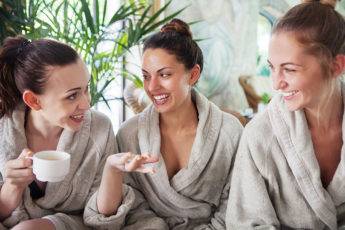 Three young happy women drinking tea at spa resort