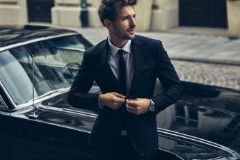 Handsome man in black suit with old classic car