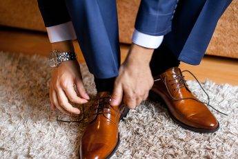 A man ties up his shoelaces on his brown shoes