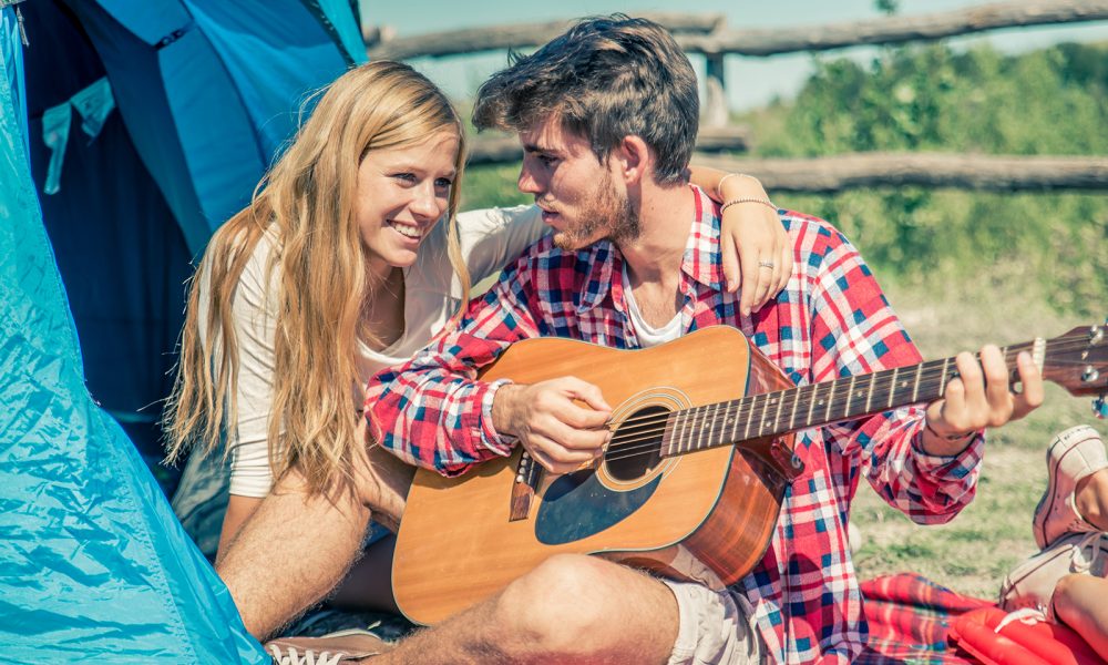 young-love-young-couple-camping-while-man-plays-guitar-1000x600