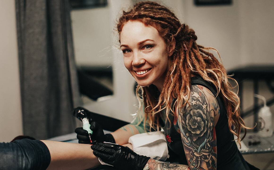 wick-dreadlock-care-tips-smiling-woman-doing-tattoo-in-dreadlocks