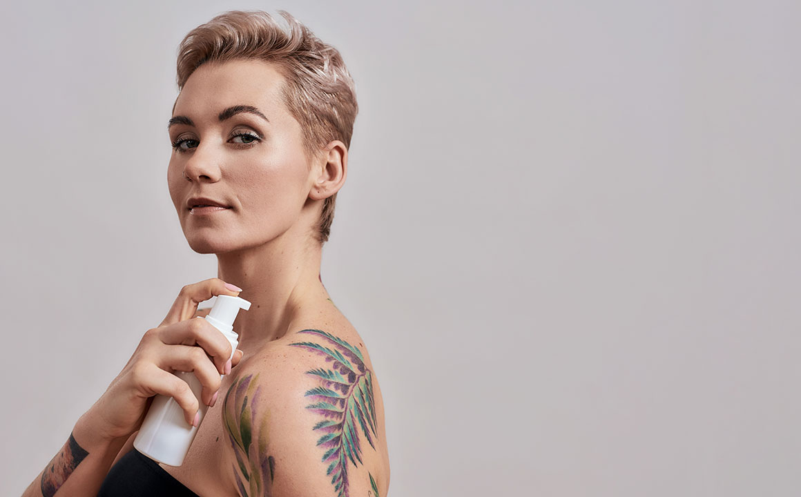 woman-putting-lotion-on-body-tattoo