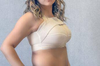 Young woman in beige compression bra bandage after breast augmentation surgery mammoplasty. banner. advertising. copy space.