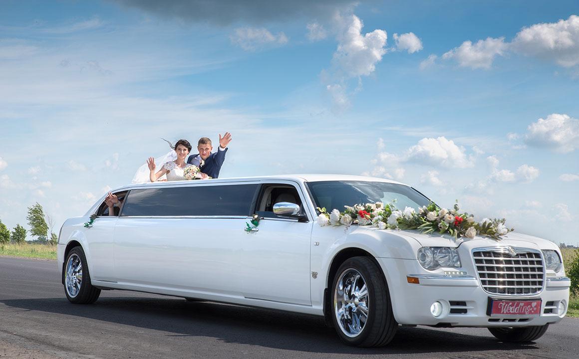 The bride and groom near the wedding limousine.